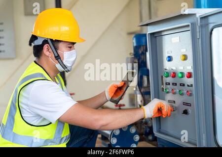 Asiatischer Ingenieur überprüft die breite Palette der Druckerhöhungspumpe bei Wasserwerk Stockfoto