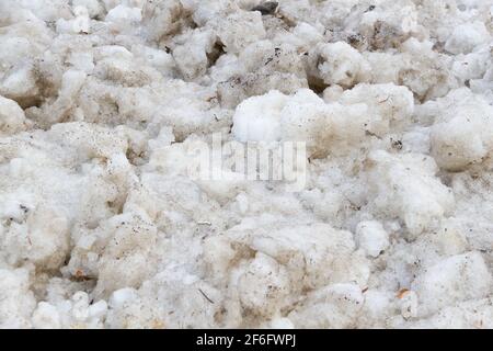 Früher Frühling schmutziger grauer geschmolzener Schnee mit Sandmuster Textur Stockfoto