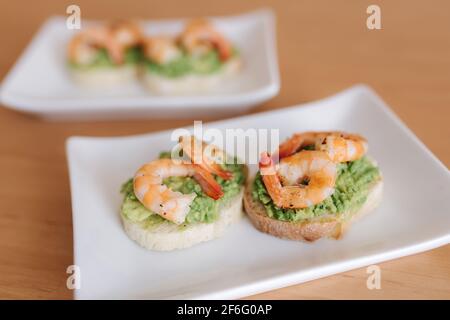 Gesunde Vorspeise von Bruschetta mit Guacamole Garnelen Nahaufnahme zu sehen. Gebratene Shrimps und pürierte Avocado auf einem gerösteten Brot Stockfoto