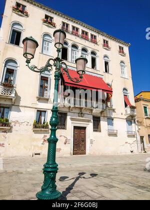 Traditionelle alte Hausfassade mit rotem Balkon und Laternenpfosten in der Straße von Venedig, Italien Stockfoto