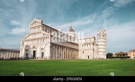 Schiefer Turm von Pisa (aufwendig geschmückter Turm aus dem 14. Jahrhundert) und Kathedrale von Pisa (marmorgestreifte Kathedrale) auf sommerlich grünem Gras und blauem Himmel. Tr Stockfoto