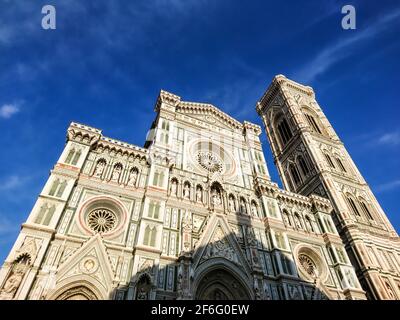 Kathedrale Santa Maria del Fiore. Wahrzeichen 1200s Kathedrale farbigen Marmorfassade und Giotto Glockenturm schließen sonnigen Blick mit blauen Himmel Hintergrund. Tr Stockfoto