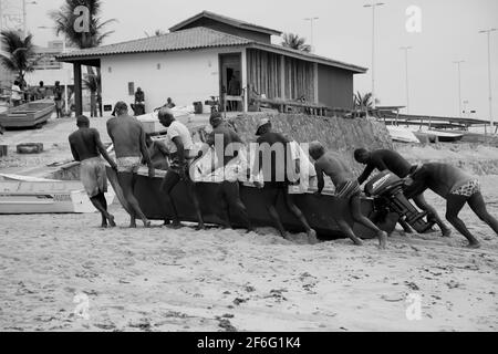 salvador, bahia, brasilien - 18. dezember 2020: Fischer werden gesehen, wie sie ein kleines Fischerboot in der Nähe der Fischerkolonie am Strand von Pituba in Salvador schieben. *** Stockfoto