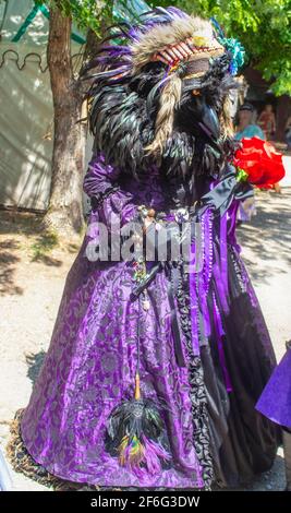 Person in verzierten Kostüm mit Rabenkopf und Schnabel und American Indian Stil Feder Kopfress und lila Brokat Kleid an Oklahoma Renassiance Festiva Stockfoto