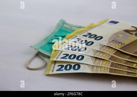 200-Euro-Banknoten, gebrannt mit medizinischer Maske, isoliert auf Weiß Stockfoto