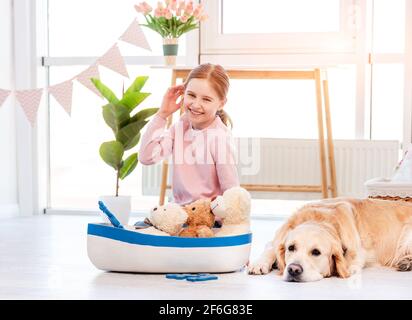 Kleines Mädchen spielen mit Seeschiff mit goldenem Retriever Hund Stockfoto