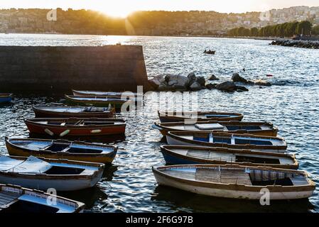 Alte hölzerne Fischerboote, die bei Sonnenuntergang auf dem Golf von Neapel, Italien, auf einem Pier neben dem Castel dell'Ovo (Egg Castle) festgemacht wurden Stockfoto