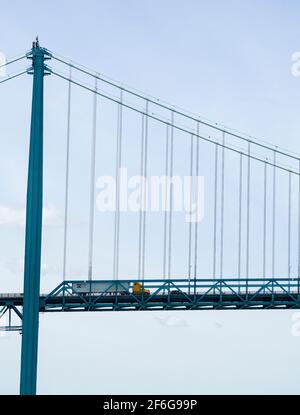 LKW Überfahrt in die USA über die Ambassador Bridge: Ein gelber Sattelzugmaschine fährt auf dem Bett der Ambassador Bridge in Windsor über Detroit Michigan, USA. Ein wichtiges Bindeglied für beide Länder. Stockfoto