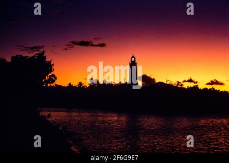 Hopetown Lighthouse in Afterglow: Hoch im Hafen von Hopetown steht der Lighthouse in einer Silhouette, die vom Nachleuchten eines feuern Sonnenuntergangs erleuchtet wird. b78,33 Stockfoto