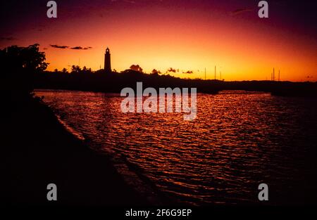 Hopetown Lighthouse in Afterglow: Hoch im Hafen von Hopetown steht der Lighthouse in einer Silhouette, die vom Nachleuchten eines feuern Sonnenuntergangs erleuchtet wird. b78,33 Stockfoto