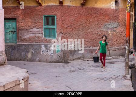 Junge Mädchen tragen Wasser in den Straßen der blauen Stadt Jodhpur in Rajasthan, Indien Stockfoto