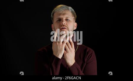 Stilvoller junger Mann mit blauen Augen, der die Kamera anschaut, posiert, Glück fühlt, Spaß macht, Freude macht Stockfoto
