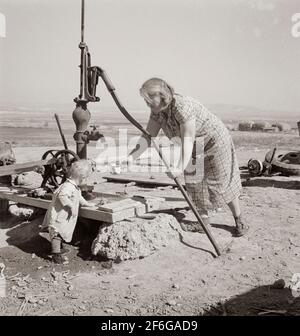 Frau Soper mit dem jüngsten Kind am Brunnen. Willow Creek Area, Malheur County, Oregon. 1939. Foto von Dorothea lange. Stockfoto