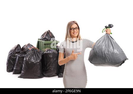 Junge Frau, die eine Plastiktüte vor die Mülltonnen hält Und zeigt isoliert auf weißem Hintergrund Stockfoto