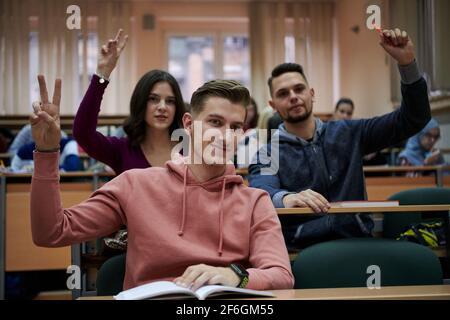 Im Klassenzimmer Multiethnische Studenten Hören Sie einem Dozenten zu und schreiben Sie in Notizbüchern. Intelligente junge Menschen studieren an der Hochschule. Stockfoto