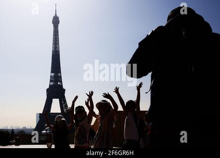 Paris, Frankreich. März 2021. Kinder fotografieren mit dem Eiffelturm auf dem Trocadero Place in Paris, Frankreich, 31. März 2021. Um die Ausbreitung des Coronavirus zu verlangsamen und den Weg für eine allmähliche Rückkehr zur Normalität bis Mitte Mai zu ebnen, werden die Schulen in Frankreich für drei Wochen geschlossen und die in vielen Regionen bereits in Kraft getretenen Einschränkungen der Volksbewegung auf das gesamte Gebiet ausgeweitet. Präsident Emmanuel Macron kündigte am Mittwochabend an. Kredit: Gao Jing/Xinhua/Alamy Live Nachrichten Stockfoto