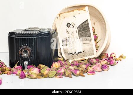 Alte Erinnerungen; Omas alte Baby-Brownie-Kamera, alte Fotos und getrocknete Rosen. Stockfoto