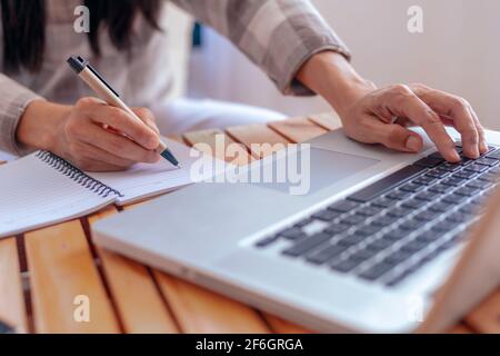 Nahaufnahme junge Geschäftsfrau Hände mit Stift Schreiben Notizen auf Papier. Weibliche Führungskraft sitzt am Tisch im Home Office. Die Hände der Frau schreiben spiralförmig Stockfoto