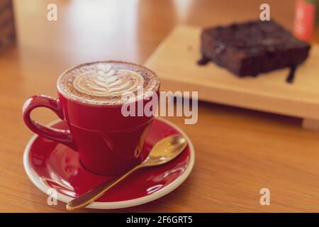 Nahaufnahme von heißem Cappuccino, Latte, Caramel Macchiato auf dem Tisch mit Blur Coffee Shop Hintergrund. Verfahren Sie mit warmen vintage Ton Stil. Stockfoto