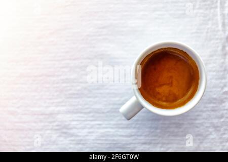 Ansicht von oben Nahaufnahme von heißem Espresso-Kaffee in einem Weiße Keramik-Tasse auf einem weißen Tischdecke Hintergrund am Morgen Stockfoto