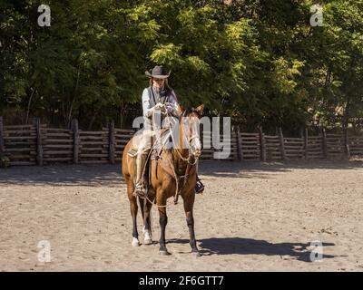 Ein Cowgirl-Wrangler bereitet ihr Lariat in einem Corral auf einer Ranch in der Nähe von Moab, Utah, vor. Sie trägt Lederbeine, um ihre Beine vor dornigen Bürsten auf der R zu schützen Stockfoto