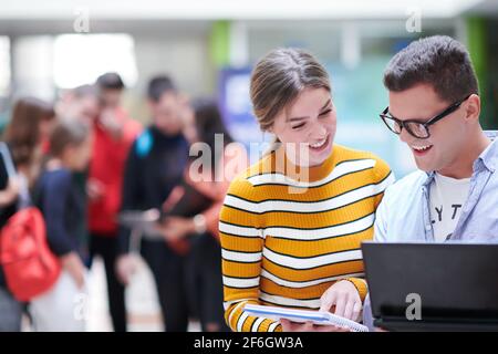 Zwei Studenten mit moderner Technik stehen dabei im Flur Warten auf den Beginn des Unterrichts Stockfoto