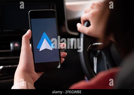CHIANG MAI , THAILAND - MAR 28, 2021: Nahaufnahme von weiblichen Fahrerinnen und Verwendung der Navigations-Anwendung Google Android Auto. Ein illustratives redaktionelles Bild. Stockfoto