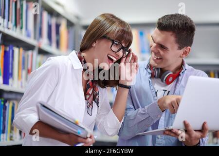 Zwei Schüler mit moderner Technik stehen in der Schulbibliothek Stockfoto