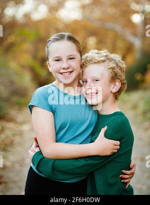 USA, Kalifornien, Mission Viejo, Portrait eines lächelnden Bruders (10-11) und einer Schwester (12-13), die sich im Wald umarmen Stockfoto