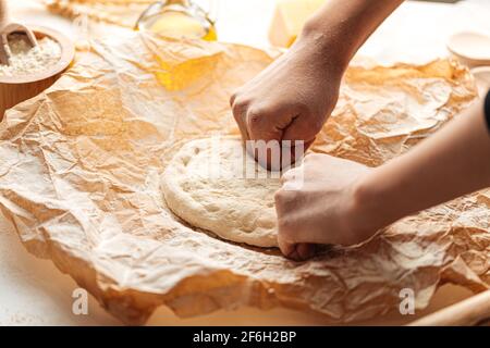 Teig zum Pizzabäcken auf dem Papier kneten Stockfoto