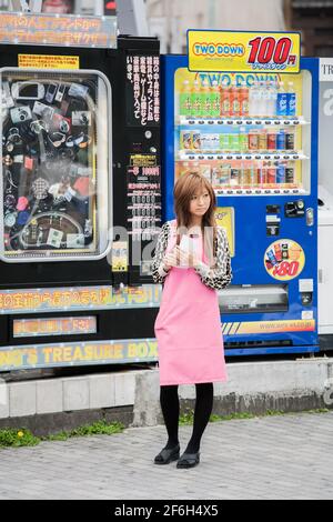 Pretty promo girl leafletting vor Automaten, Ikebukuro, Tokio, Japan Stockfoto