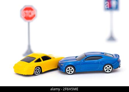 Unfall mit zwei Spielzeugautos und Schild auf weiß isoliert. Konzeptbild über Unfall auf der Straße Stockfoto