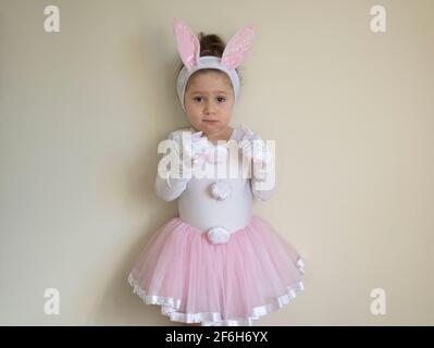 Selektiver Fokus. Hübsches kleines Mädchen in einem Osterhasen Kostüm steht aufgeregt vor der Wand. Stockfoto