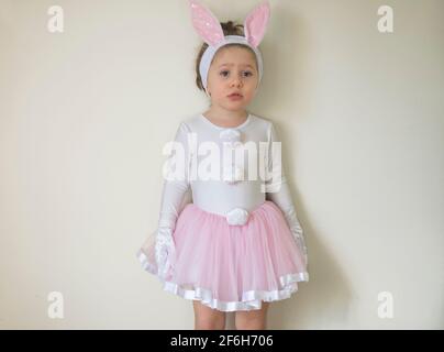 Selektiver Fokus. Hübsches kleines Mädchen in einem Osterhasen Kostüm steht aufgeregt vor der Wand. Stockfoto