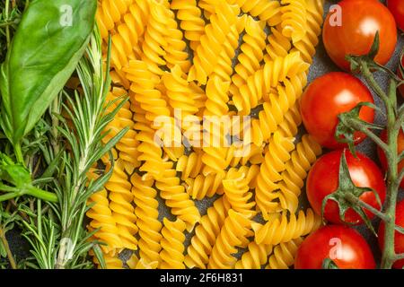 Rohe Fusilli-Pasta mit Tomaten, Kräutern und Basilikum. Italienische Pasta mit Zutaten in den Farben der italienischen Flagge. Hochwertige Fotos Stockfoto