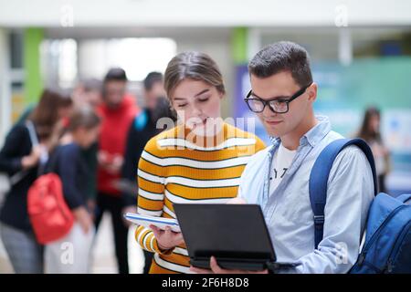 Zwei Studenten mit moderner Technik stehen dabei im Flur Warten auf den Beginn des Unterrichts Stockfoto