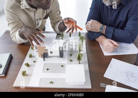 Nahaufnahme des Architekturmodells mit Neubau und Architekten sitzen am Tisch und diskutieren Entwicklung von neuen Bereich Stockfoto