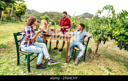 Fröhliche Leute, die Spaß beim Rotwein im Weinberg haben - Junge Freunde genießen gemeinsam die Erntezeit auf dem Bauernhof Haus Stockfoto
