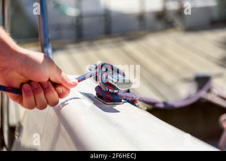 Mann Hand mit Boot Seil, Segler binden Seeknoten. Menschliche Hand auf Segelboot oder Yacht, die einen Knoten bindet, Nahaufnahme Stockfoto