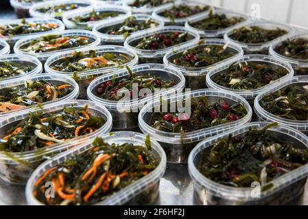 Verschiedene Fische und chuka Wakame laminaria Algensalat in Kunststoff-schalen. Konzept der gesunden Lebensmittelproduktion oder Lieferung von Lebensmitteln Stockfoto