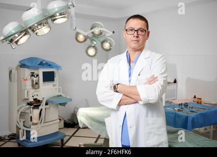 Männlicher Arzt im Laborkittel, der im Operationssaal steht. Stockfoto