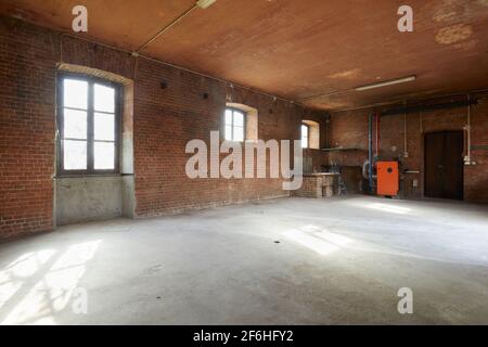 Altes Werkstattinterieur mit Ziegelwänden und Fenstern, Sonnenlicht Stockfoto