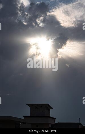 Helles Sonnenlicht Sonne scheint durch Wolkenloch über dem Gebäude. Stockfoto