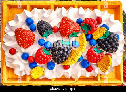 Waffel mit Eis, Erdbeeren und anderen Früchten als Plastikschild. Stockfoto