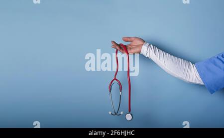 Arzthand mit Stethoskop isoliert auf blauem Hintergrund Stockfoto