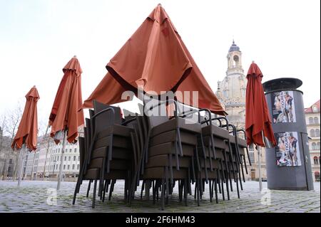 Dresden, Deutschland. April 2021. Vor einem geschlossenen Restaurant auf dem Neumarkt vor der Frauenkirche stehen Stühle übereinander. Aufgrund der hohen Anzahl von Corona-Infektionen werden die Relaxationen in Dresden ab dem 01. April 2021 rückgängig gemacht. Quelle: Sebastian Kahnert/dpa-Zentralbild/dpa/Alamy Live News Stockfoto