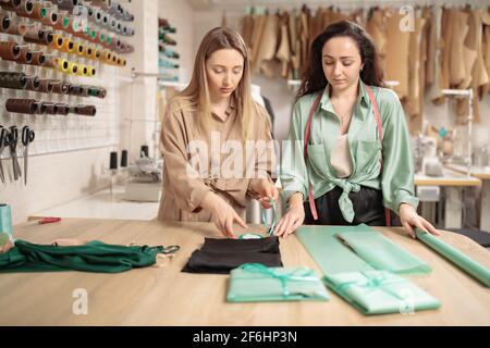 Zwei junge Modedesigner oder Schneider beim Verpacken neuer Kleidung Vor der Lieferung in Werkstatt-Studio Stockfoto