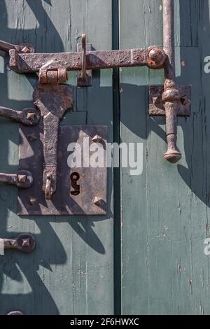 Detailansicht eines alten Türschlosses auf einer alten Holztür, rostiger Metallmechanismus... Stockfoto