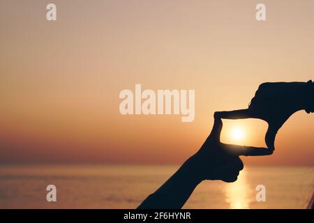 Selektive Fokussierung der Hände von Frauen, die Bild für Finger Geste mit Sonnenaufgang auf dem Berg machen, Frauen erfassen Sonnenaufgang oder Sonnenlicht im Freien. Zukünftige Planung CO Stockfoto