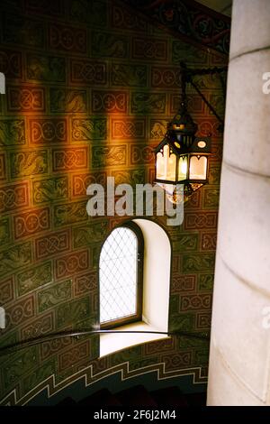 Antike Wandleuchte auf einer Wendeltreppe im Schloss Neuschwanstein. Stockfoto